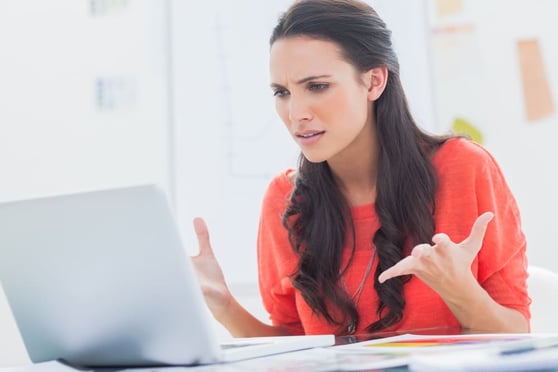 Annoyed designer gesturing in front of her laptop in her office